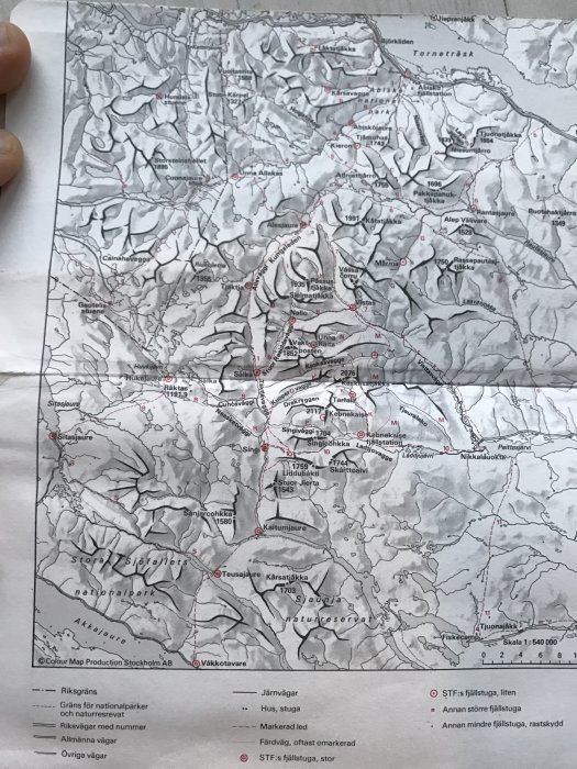 Svartvit topografisk karta över ett fjällandskap med markerade vandringsleder, stugor och rutter.