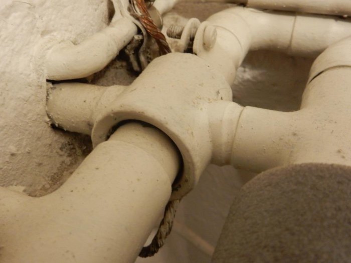 Närbild på rörkopplingar och isolering i ett VVS-system under renovering.