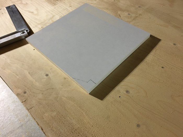 MDF-skiva med markerat urspårningsmönster ovanpå en arbetsbänk av trä.