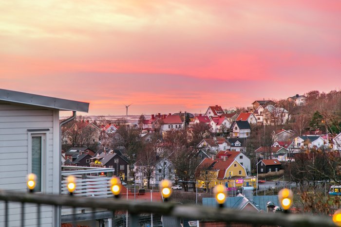 Utsikt från villa över tätbebyggd stadsdel med färgglad himmel vid solnedgång.