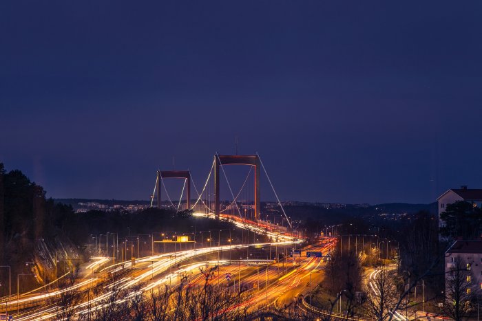 Utsikt över en belyst bro med trafikstråk i skymningen, synlig från en villa.