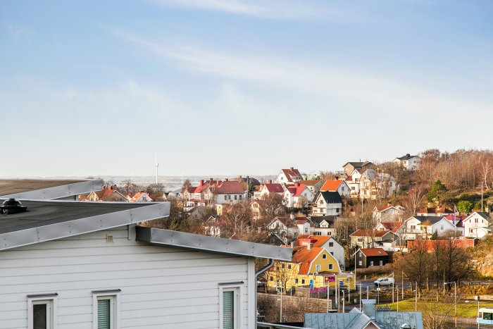 Utsikt från en villa över en pittoresk stad med färgglada hus och vindkraftverk i bakgrunden.