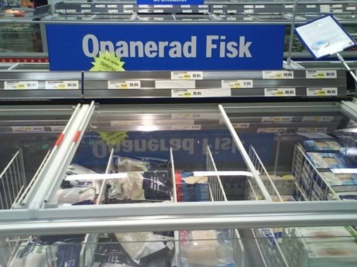 Kyldisk med skylt som säger "Onanerad Fisk" i en mataffär, med prislappar och fiskförpackningar.