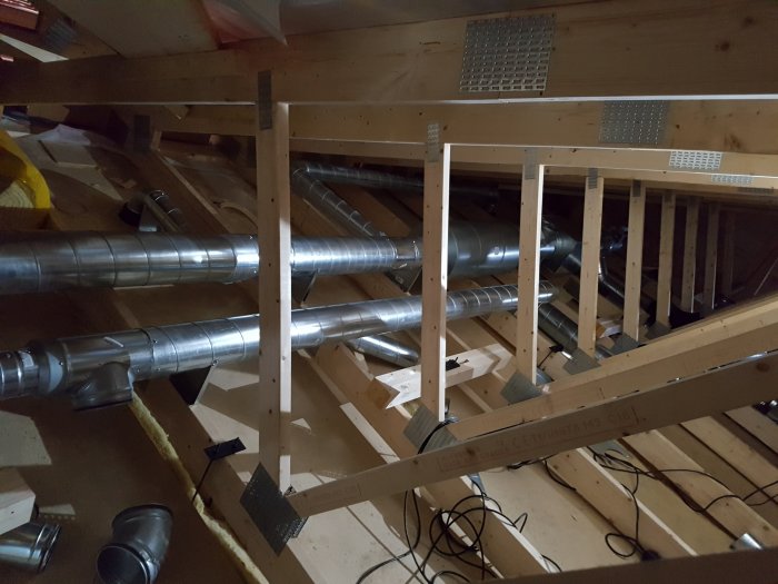 Vind med trästomme och isolering som visar installation av ventilationsrör och kabeldragning.