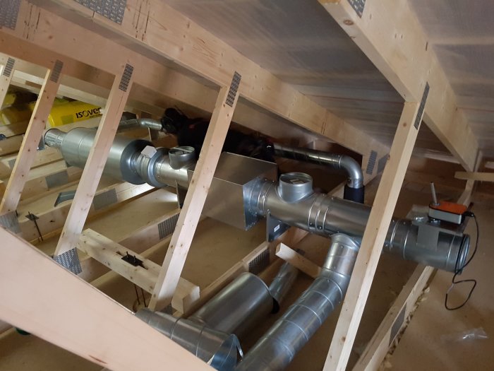 Uppförande av ventilationssystem mellan träbjälkar i ett oavslutat byggloft.