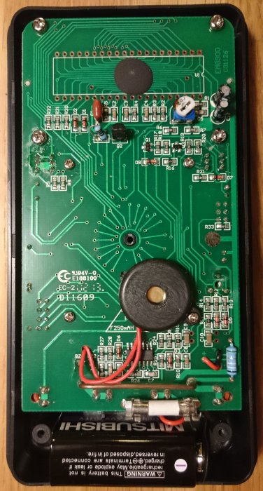 Innandömet av en Biltema 17-238 multimeter med kretskort, komponenter och säkringar.