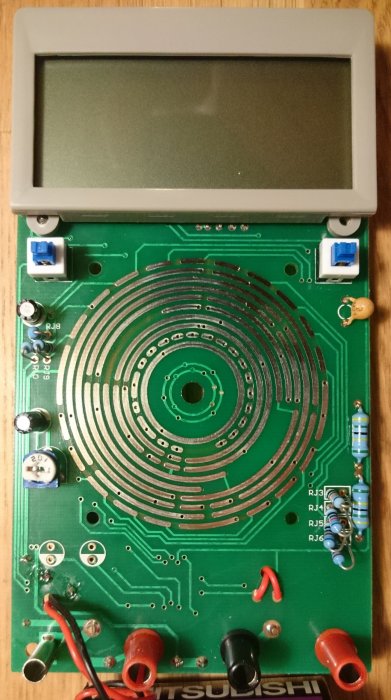 Öppnad digital multimeter som visar grönt kretskort, stora säkringar och terminaler med en grå display ovanför.