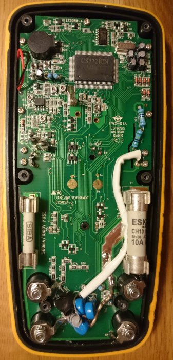 Innandömet av en Biltema 17-238 multimeter med kretskort märkt EX505A, stabil terminaler och säkringar.