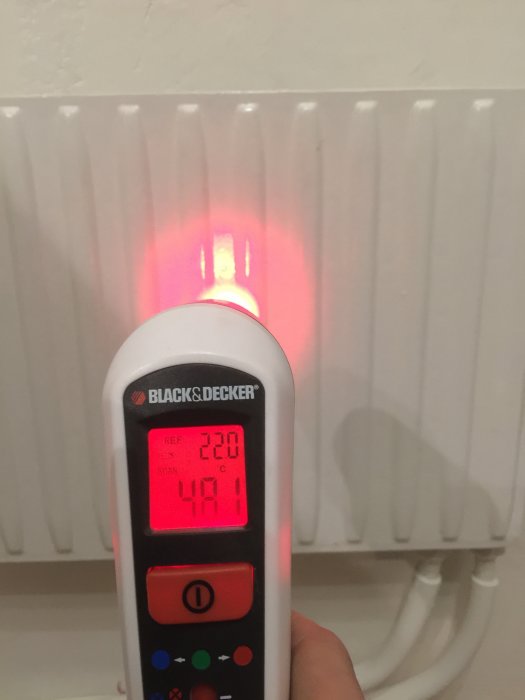 Infraröd termometer visar 47.1 grader Celsius på en varm radiator.