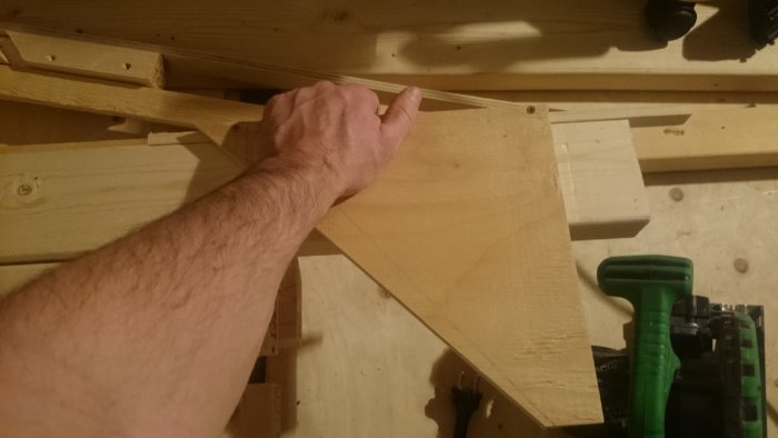 Hand håller en träklämma på en klyvsågsstöd med inställbar vinkel.