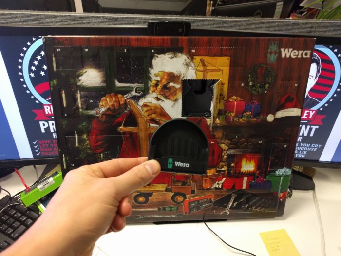 Hand håller en verktygskalender med öppnad lucka på en arbetsplats, innehåller skruvmejslar från Wera och julinspirerat motiv.