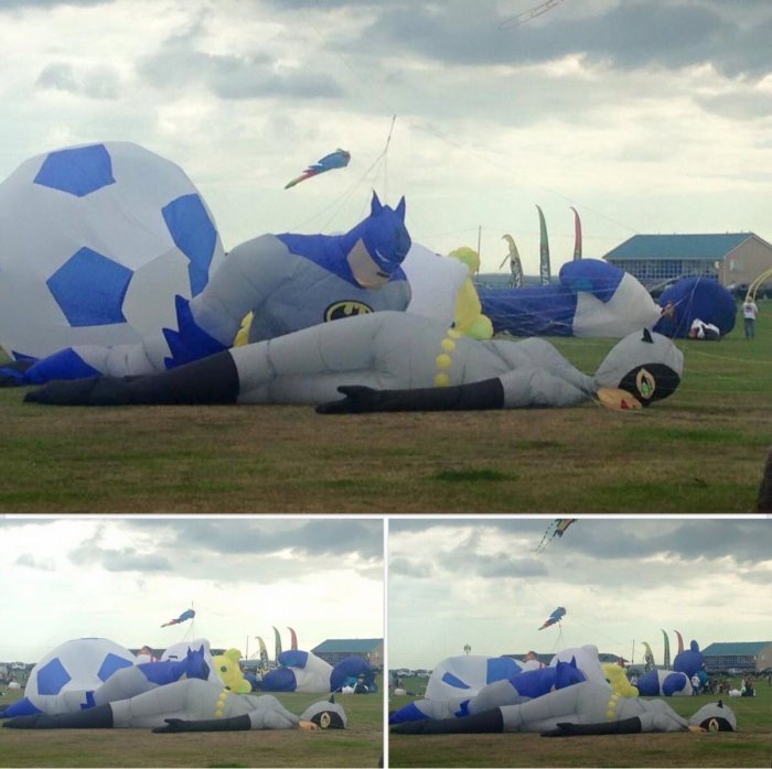 Stort uppblåsbart Batman-drake ligger på marken vid drakfestival, med andra drakar i luften.