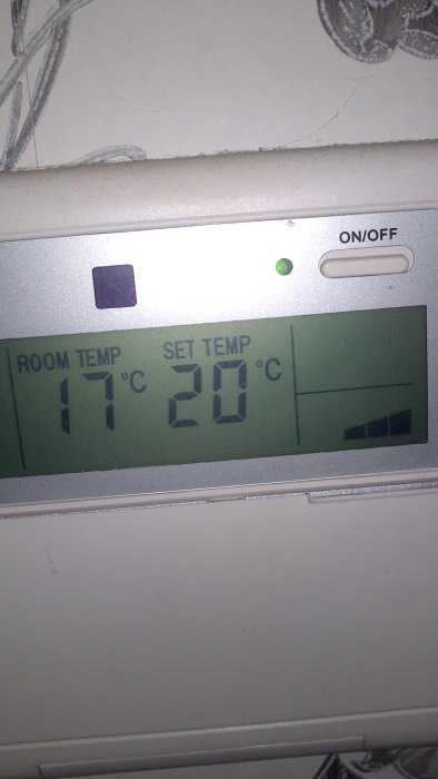 Termostat visar rumstemperatur på 17°C och inställd temperatur på 20°C med en grön lysdiod som lyser.