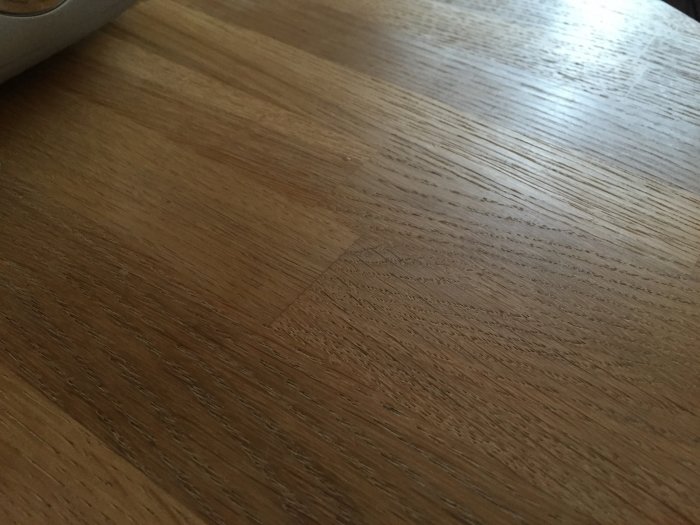 Närbild på en skarvad träskiva av ek som visar den tydliga träfiberstrukturen även efter täckmålning.