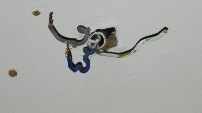 Elektriska kablar sticker ut ur ett hål i en vägg, redo för installation av lampa eller fläkt.