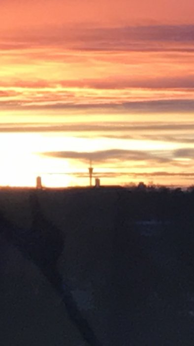 Solnedgång med silhuett av ett torn mot färggrann himmel.