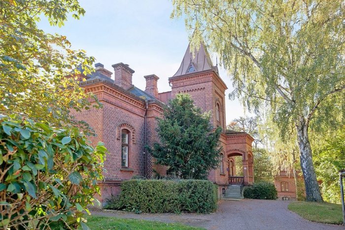 Pampig tegelvilla från 1889 i Professorstaden i Lund, omgiven av grönska och med historiska detaljer.