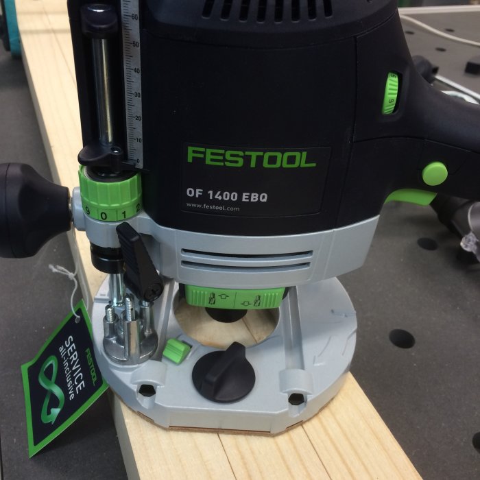 En överfräs från Festool, modell OF 1400 EBQ, på ett arbetsbord med märket synligt.