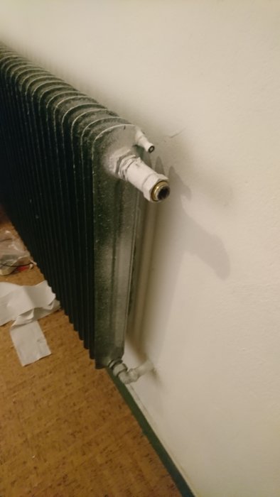 Vattenburet radiator-element utan termostat mot vit vägg, synliga anslutningsrör.