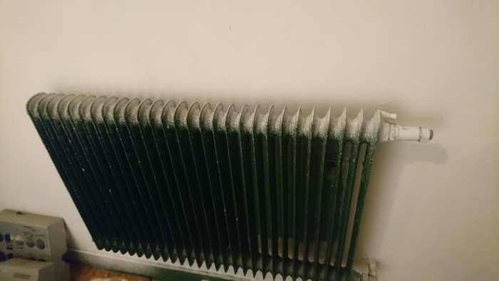 Vattenburet element som inte värms upp, parkettgolv och urkopplad termostat syns.