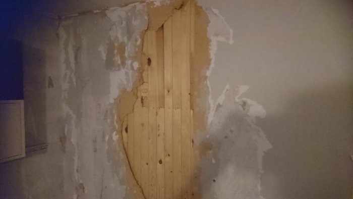 Renoveringsprojekt med bortriven tretexvägg som avslöjar underliggande råspont.