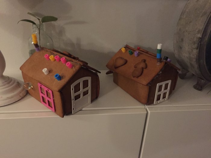 Två pepparkakshus dekorerade med Lego och pärlor av barn.