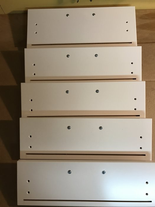 Vita IKEA lådfronter på en rad, modifierade med notfräsningar och skruvhål.