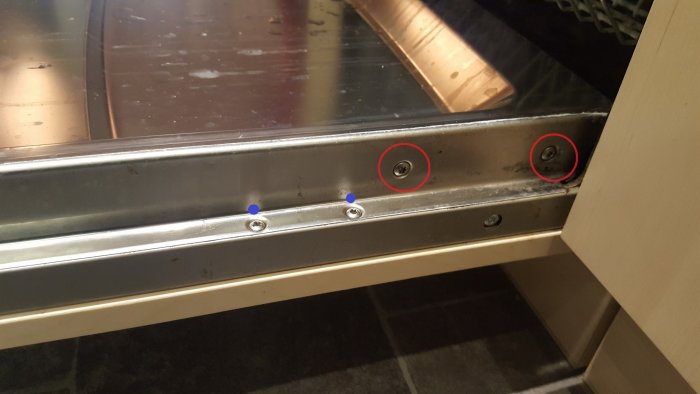 Dishwasher front plate with screws marked in blue and red circles indicating points of interest in a repair discussion.