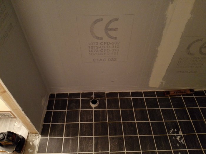 Renovering av källardusch med 10x10 klinkergolv och delvis kaklade väggar, mätermarkeringar och verktyg syns.