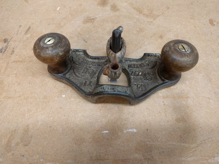 Antik Stanley 71 handhyvel med delvis avrostade delar placerad på ett arbetsbord.