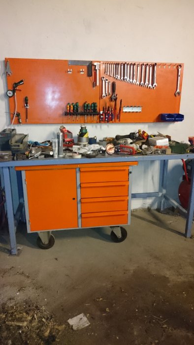 Nyrenoverad verktygsvagn i orange med verktygstavla och verktyg mot en vägg i ett verkstadsutrymme.