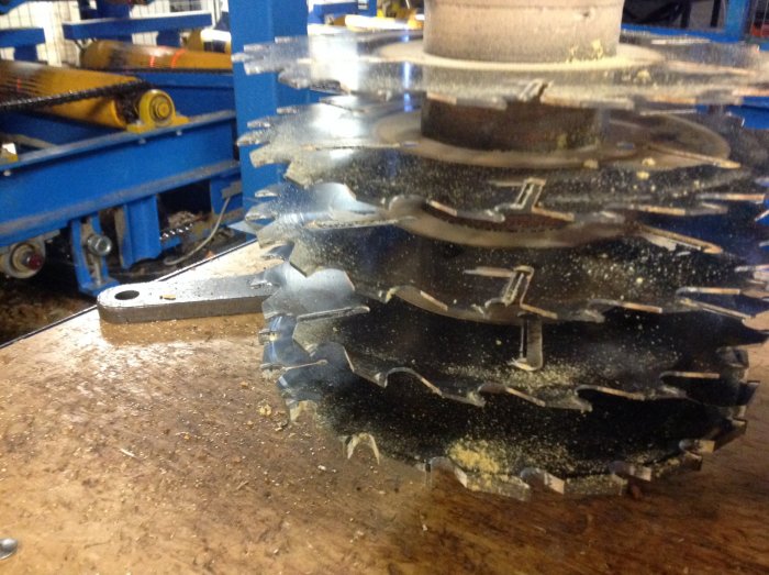 En samling staplade sågklingor med sågspån på ett arbetsbord i en verkstad, redo för morgondagens träbearbetning.