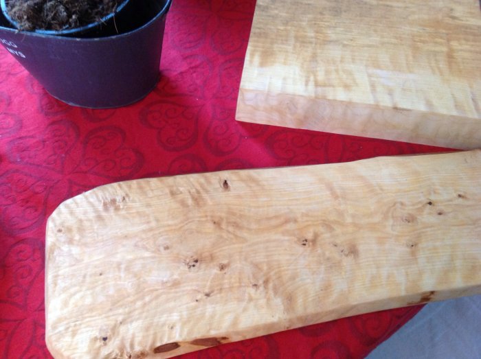 Två utsågade träbitar med naturliga mönster på ett rött tyg, återanvända som hobbyprojekt.