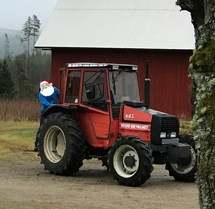 Barn i blå jacka på pallyften av en röd Volvo BM Valmet traktor på en gård.