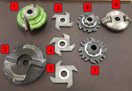 Samling av olika träbearbetningsfräsar och kuttrar med numrerade etiketter på en bordsskiva.