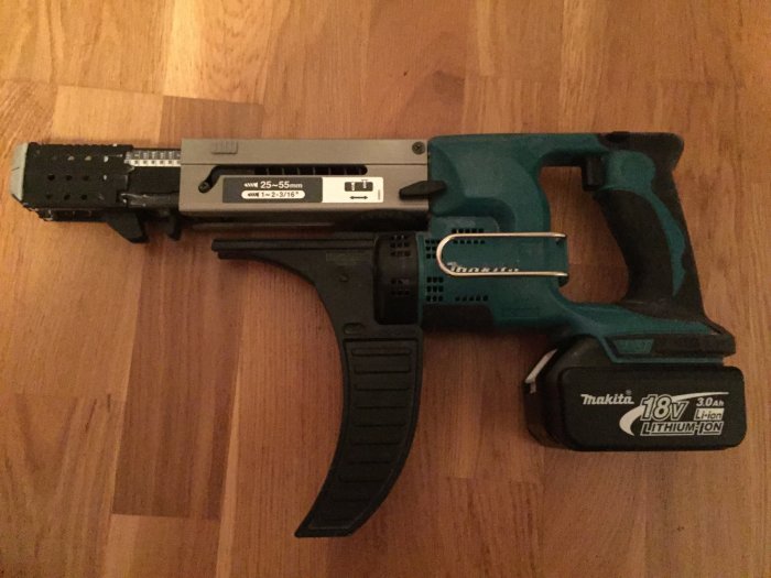Makita batteridriven gipsskruvdragare med dubbla batterier och laddare på ett trägolv.