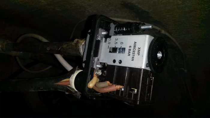 Översikt av en tryckvakt för en vattenpump med inställningar synliga och otäckt kopplade kablar.