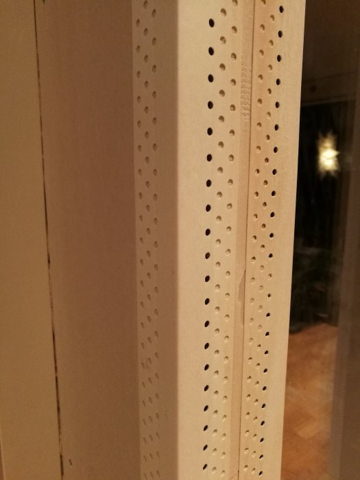 Närbild på ett hörn där två gipsväggar möts med AquaBead gipshörn synliga och hålade för spackling.