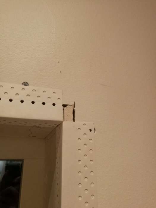 Nyinstallerat fönster med AquaBead gipshörn och synlig gipsskruv i en vägg, redo för spackling.