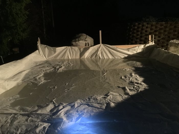 Byggarbetsplats på kvällen med presenningar och påbörjade höjder i konstruktionen.