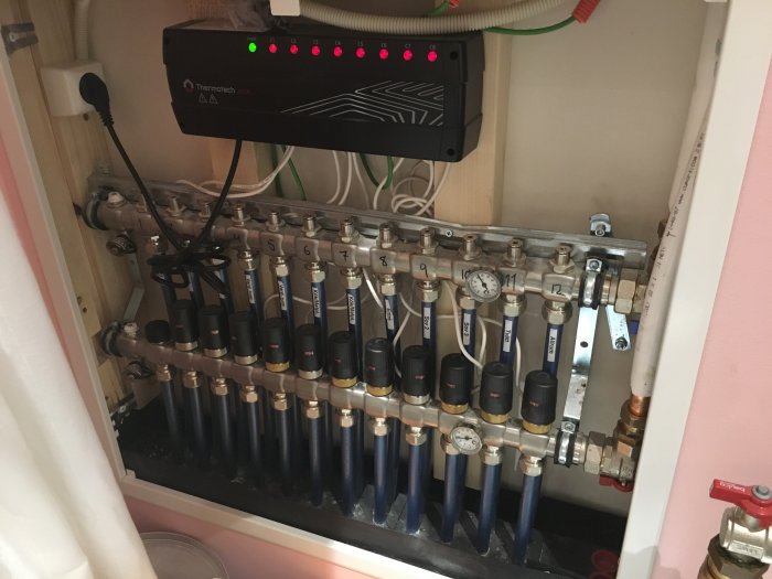 Installation av golvvärme med fördelarskåp och temperaturregleringssystem.