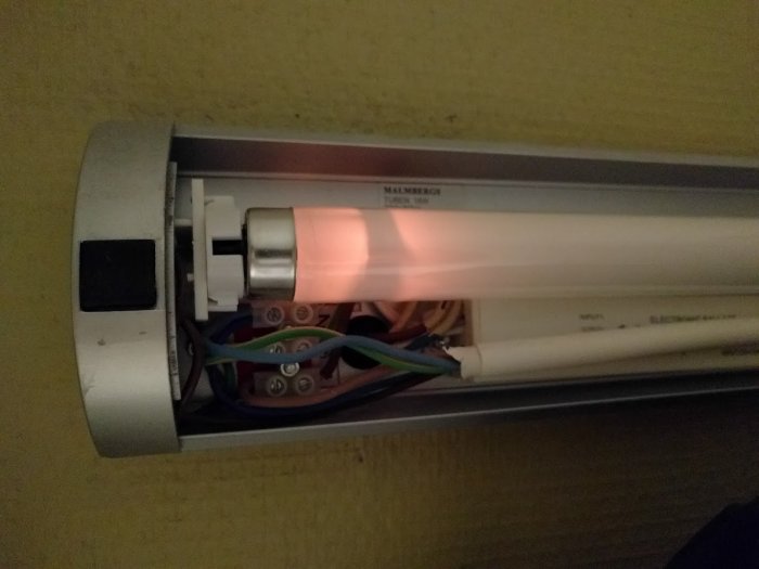 Öppnad lysrörsarmatur med lysrör och elektriska kablar synliga, indikerar problem med belysningen.