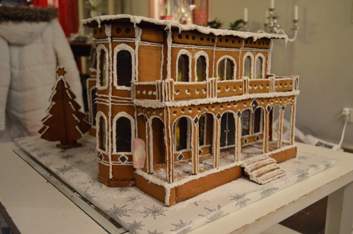 Pepparkakshus inspirerat av Victorian Italianate-stil med detaljerad dekoration och en skumtomte för storleksskala.