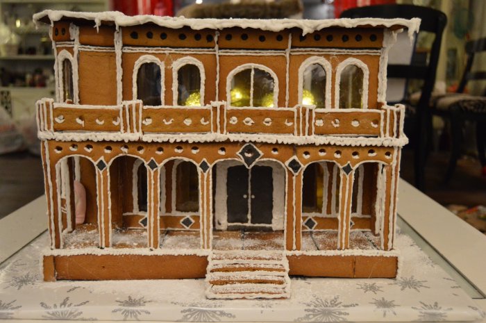 Hemgjord pepparkaksversion av ett Victorian house i Italianate style med detaljerad dekor och belysning inifrån.