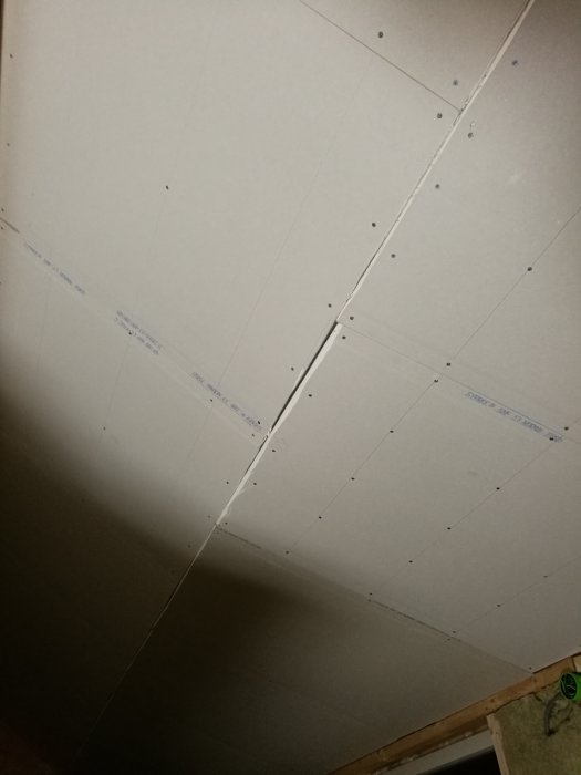 Ospacklade gipsskivor i en takkupa med synlig lutningsövergång från brantare till flackare vinkel.