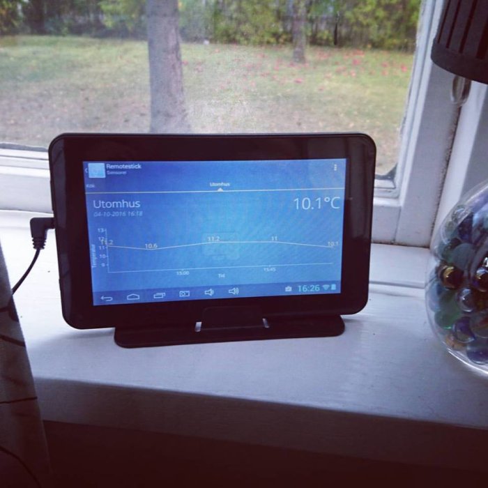 Android-enhet visar utomhustemperatur på Remotestick-appen vid ett fönster.