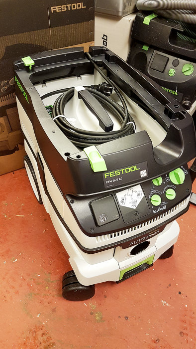 Festool CTM 26 Autoclean dammsugare uppackad på verkstadsgolvet med slang och extra plastsäckar.