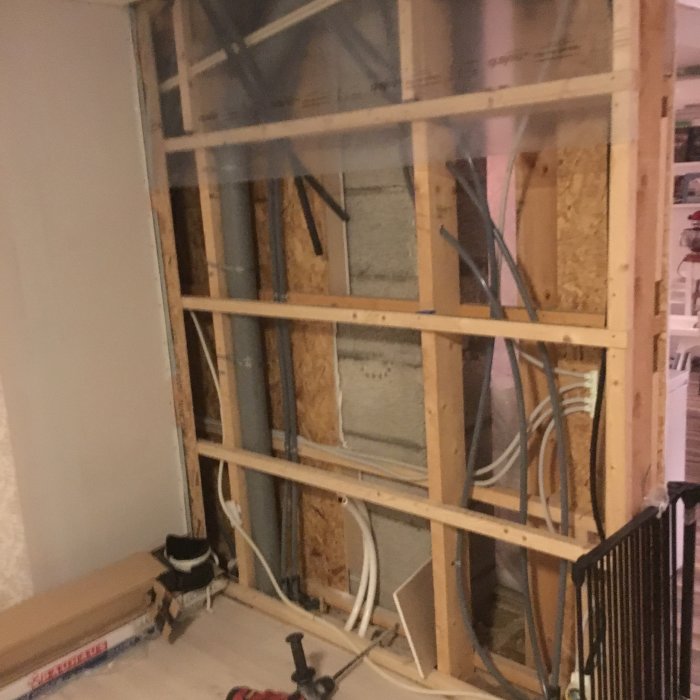Renoveringsprojekt med öppen vägg som visar isolering, träreglar och elektriska installationer.