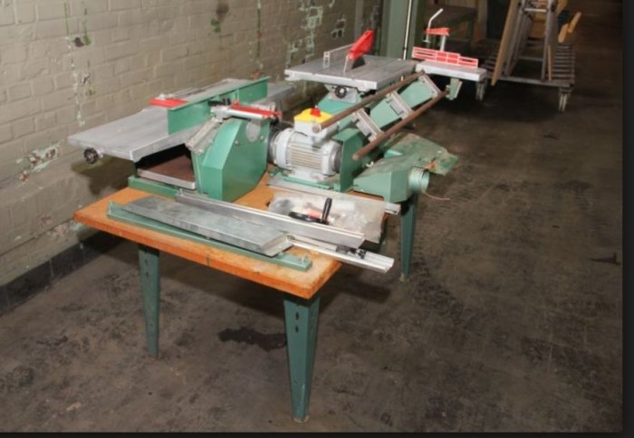 Industriell maskin med defekt strömbrytare märkt med gult på en verkstadsbänk.