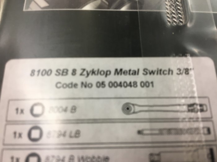 Otydlig bild på en produktetikett med texten "Zyklop Metal Switch" som antyder en verktygspresent.